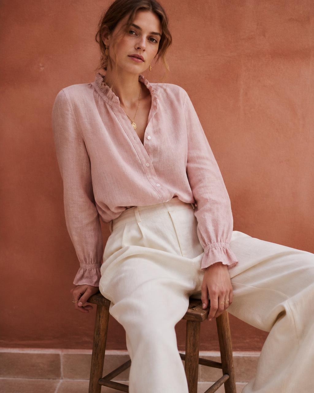 Modelo em blusa de linho rose sentada em banco de madeira